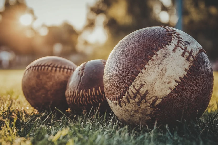 Three vintage baseballs resting on grass, symbolizing the historical legacy and timeless appeal of baseball, as featured in the sports history blog on eternalslots.com.