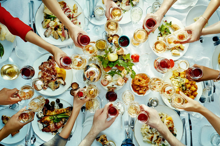 Winter dinner party celebration with guests clinking glasses over a beautiful spread of delicious dishes, creating a festive and cozy atmosphere for the holiday season.