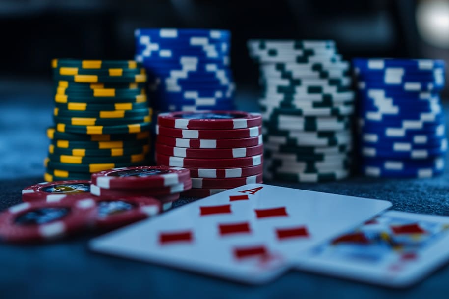 Close-up of poker chips stacked in various colors with an ace of diamonds card displayed on a casino table. Perfect for poker enthusiasts at Eternal Slots, offering exciting gameplay and strategies for winning big.