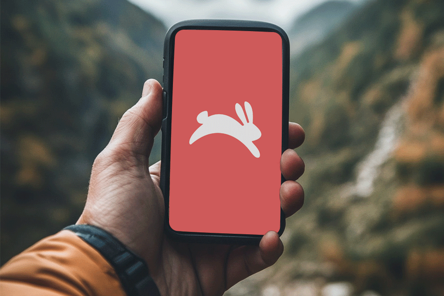 Traveler holding a phone with the Hopper app logo displayed, against a scenic mountain backdrop – showcasing smart travel booking and price prediction tools for adventurous explorers.