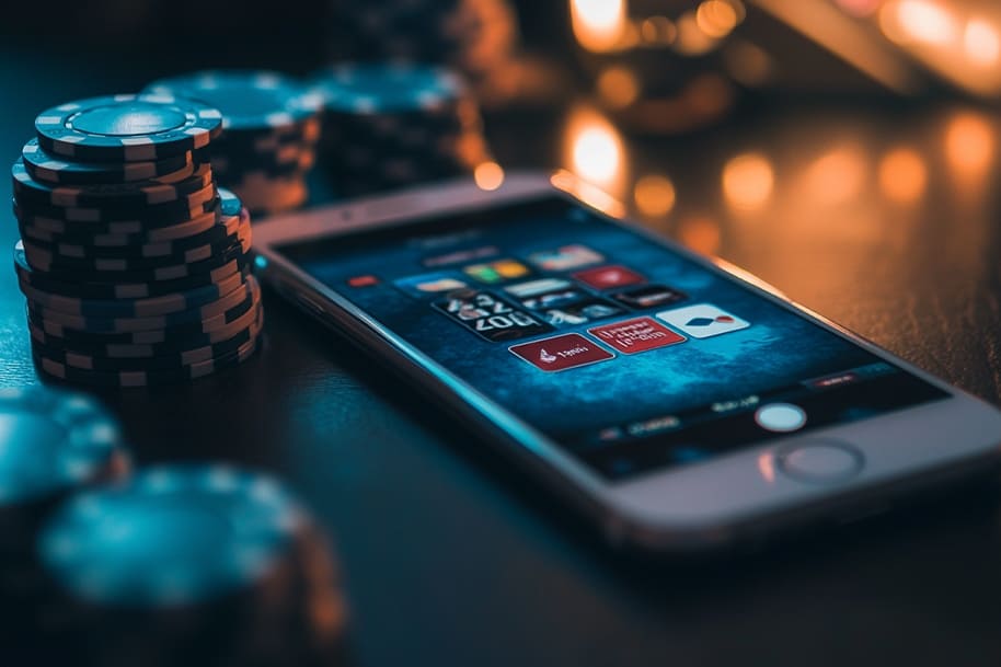 Smartphone displaying online casino game screen surrounded by poker chips representing the rise of mobile gambling from home