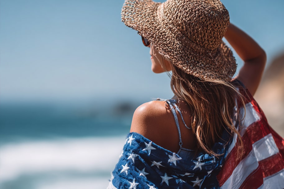 Woman wearing sunhat and American flag at the beach on Independence Day – patriotic summer getaway featured on Eternal Slots Casino blog