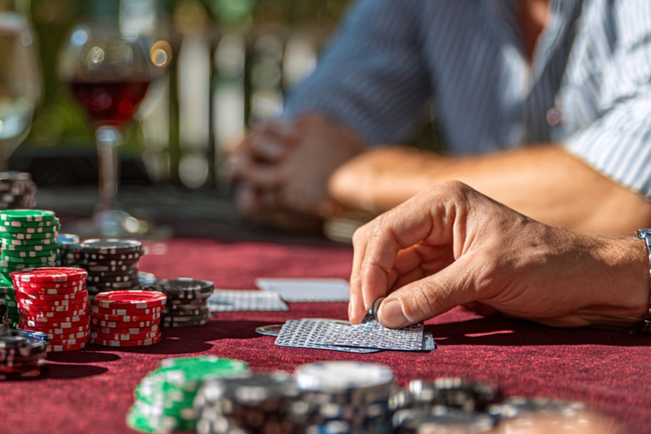 Close-up of poker chips and cards during a high-stakes casino game on a red velvet table, capturing the thrill of live play.