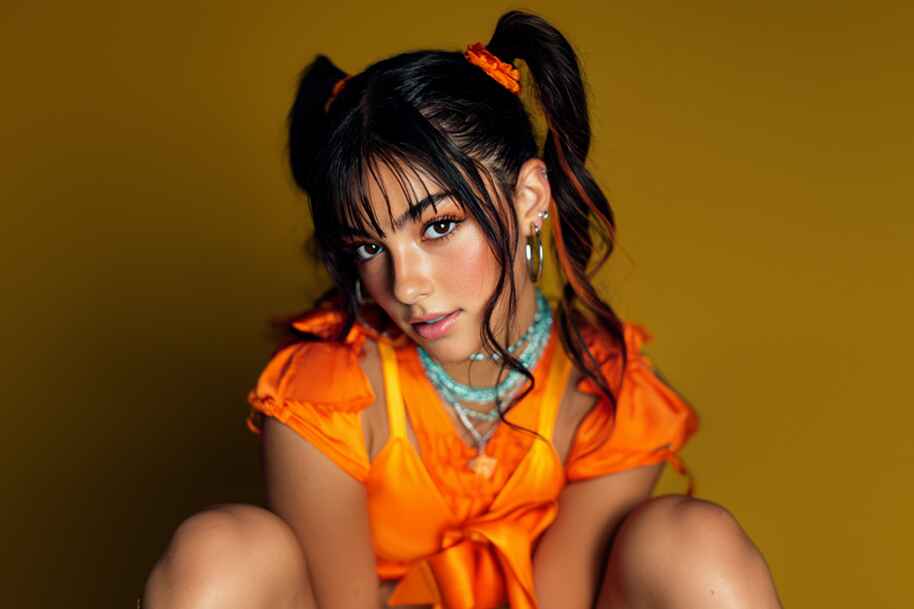 Young American influencer in a vibrant orange outfit and playful hairstyle posing confidently — featured on EternalSlots.com blog exploring influencer lifestyle, digital millionaires, and social media success in the USA.