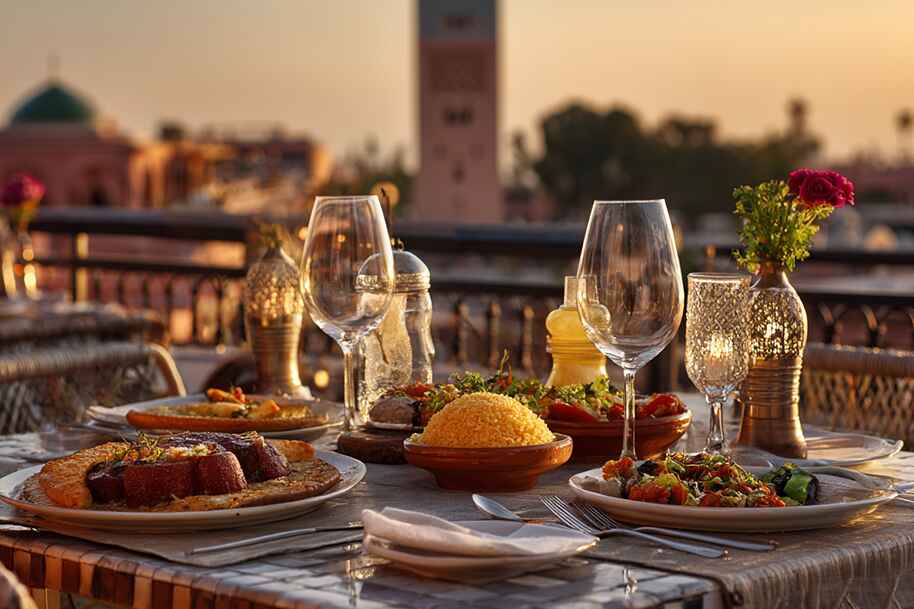 Elegant Moroccan rooftop dinner setup at sunset with traditional dishes – best food experiences in Marrakech
