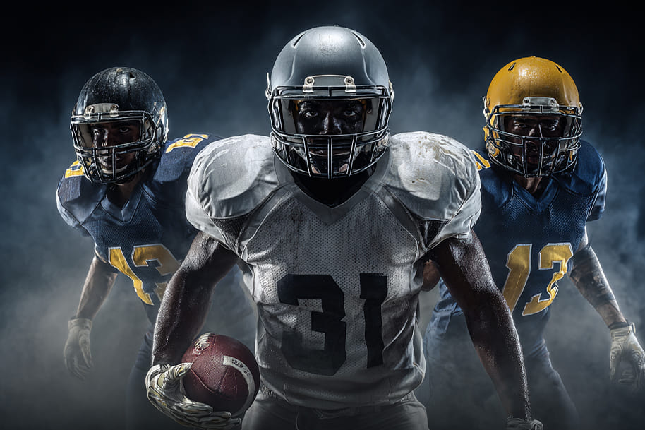 Three intense American football players in full gear, emerging from dramatic smoke.