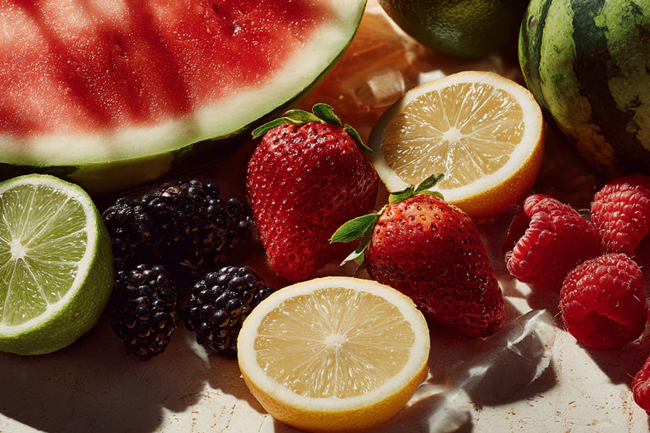 Close-up of fresh summer fruits including watermelon, strawberries, lemons, blackberries, and limes featured in EternalSlots Casino blog on seasonal recipes