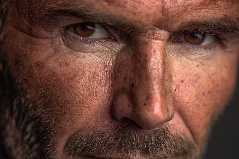 Intense close-up of a mature man with brown eyes and rugged features, symbolizing powerful celebrity life stories like the David Beckham Netflix series featured by Eternal Slots Casino