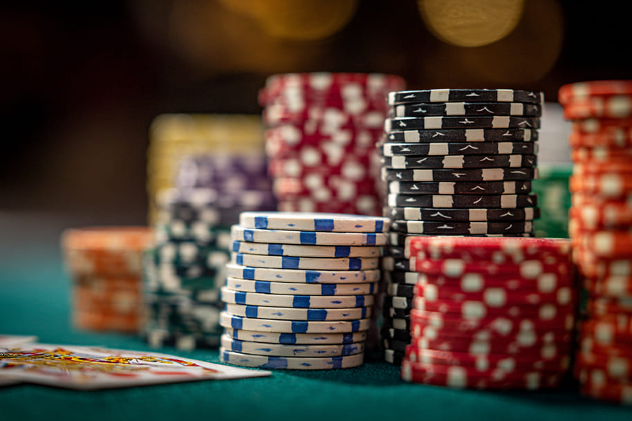 Stacks of multicolored poker chips on a casino table, representing high-stakes action and the fusion of traditional and new games.