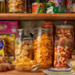 Colorful pantry shelf filled with crunchy global snacks including chips, cookies, and international treats in jars and packages – perfect for discovering unique snack foods and global snack trends for 2025.