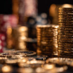 Stacks of shiny gold casino chips with poker chips blurred in the background, symbolizing deposit bonuses vs cashback rewards at Eternal Slots online casino.