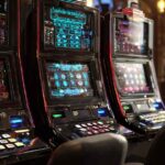 Row of modern slot machines with colorful digital displays inside a casino, showcasing advanced gambling technology and game variety at Eternal Slots Casino.