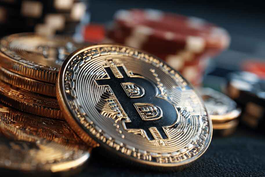 Tilted Bitcoin resting on coins with poker chips blurred in the background, illustrating cryptocurrency in gambling.