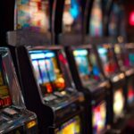 Row of brightly lit slot machines in a casino, showcasing colorful reels and flashing lights, representing the excitement of playing online slots at Eternal Slots.