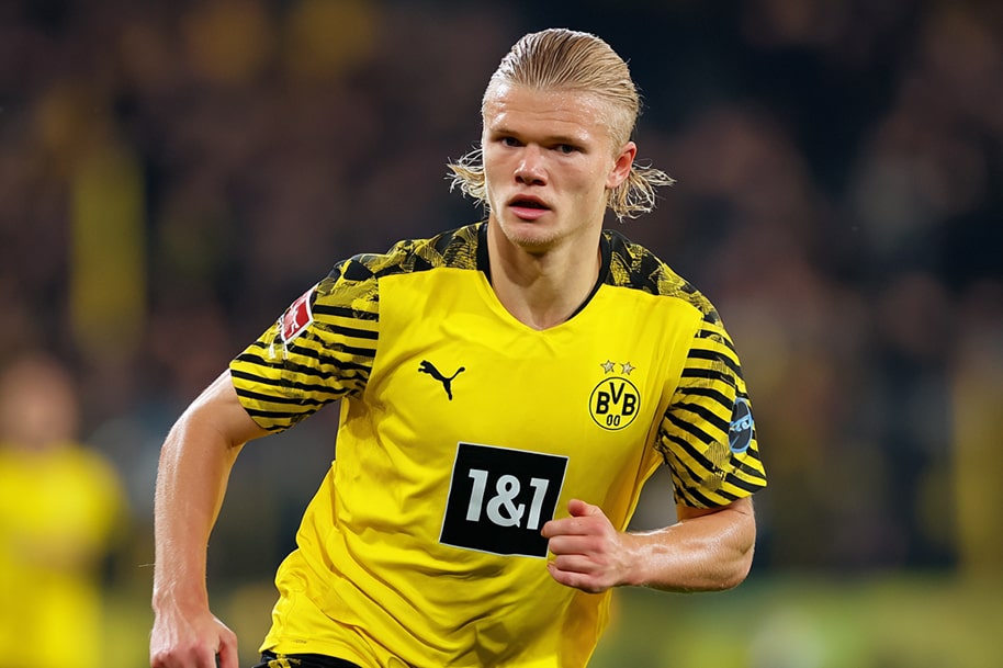 Player in yellow and black jersey running during a match, focused on the ball.