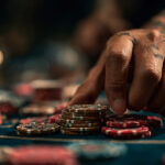 Tattooed hand stacking casino chips on a gaming table during Labor Day casino promotions, symbolizing high-stakes play and big rewards.