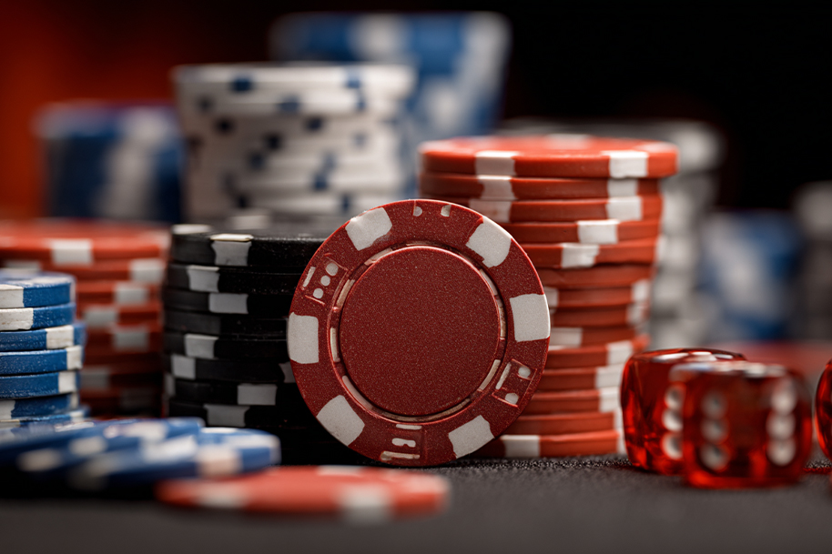 Stacks of colorful casino chips in red, black, and blue with red dice, representing Labor Day casino promotions and bonus rewards.