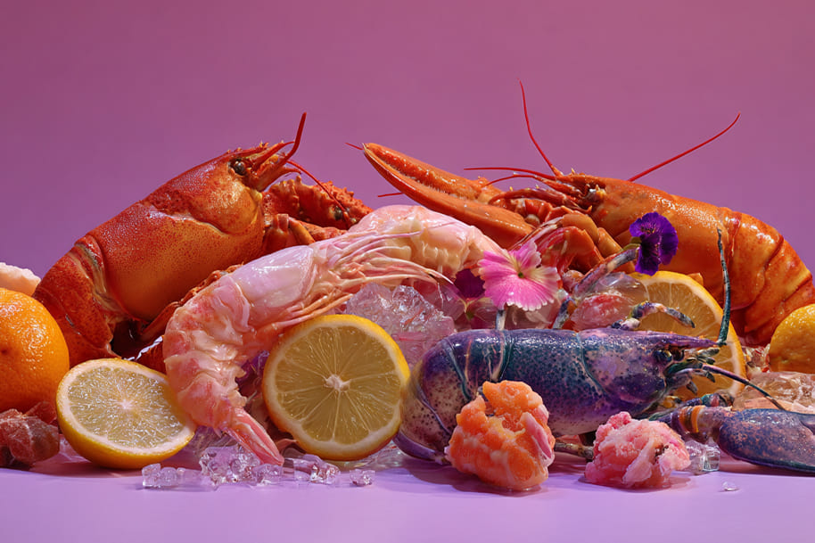 Colorful display of plant-based lobster and prawn substitutes with citrus fruits and flowers vegan seafood platter showcasing 2025 food innovations.