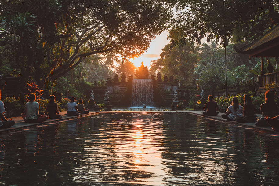 Group meditation session at Bali temple with waterfall and sunset view – spiritual and mindfulness retreat for wellness tourism 2025.