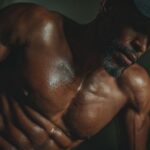 Muscular man training shirtless at home, showcasing fitness and strength from effective home workout routines for busy people