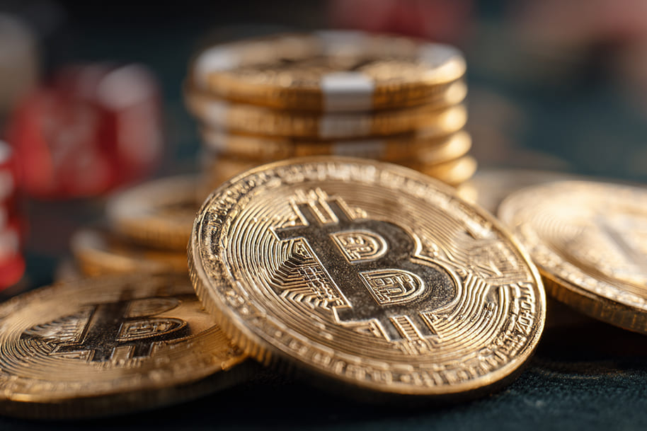 Close-up of shiny golden Bitcoin coins stacked on a casino table, symbolizing crypto gambling promotions and exclusive player rewards.