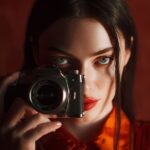 Elegant model with red lips and vintage camera, symbolizing the power of visual storytelling in influencer marketing, featured on Eternal Slots blog about social media influence.