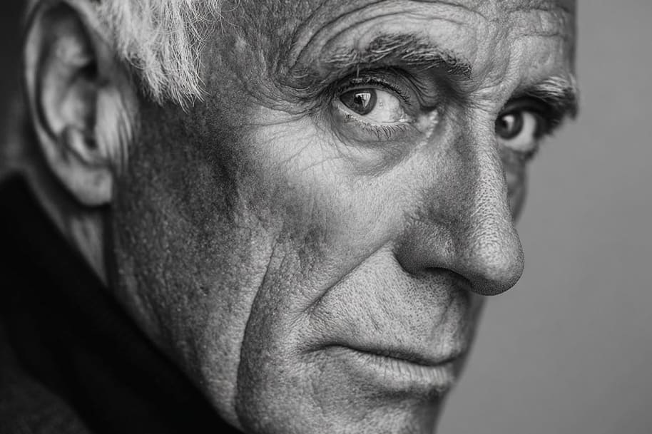 Close-up black and white portrait of Giorgio Armani with intense gaze, symbolizing sophistication and luxury fashion legacy.