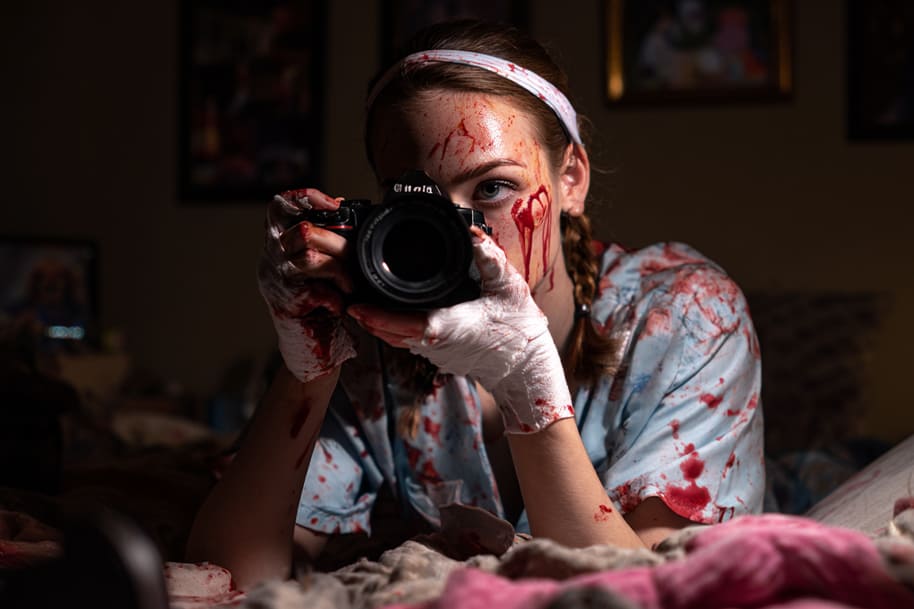 Young woman with blood-stained clothes holding a camera – dramatic true crime inspired thriller scene capturing America’s obsession with crime stories.