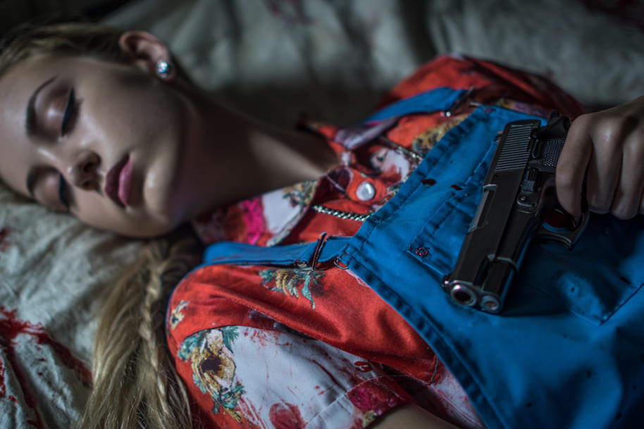 Young woman lying down holding a pistol – suspenseful and dark imagery reflecting America’s fascination with true crime series.