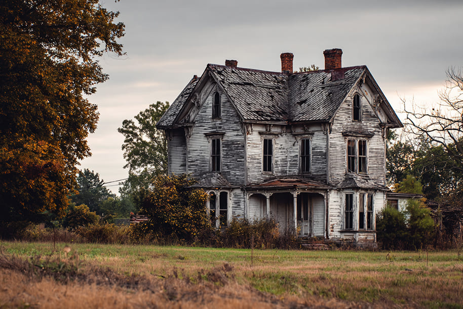 Abandoned haunted house with broken windows and decaying roof, a spooky attraction perfect for Halloween thrill seekers in October.