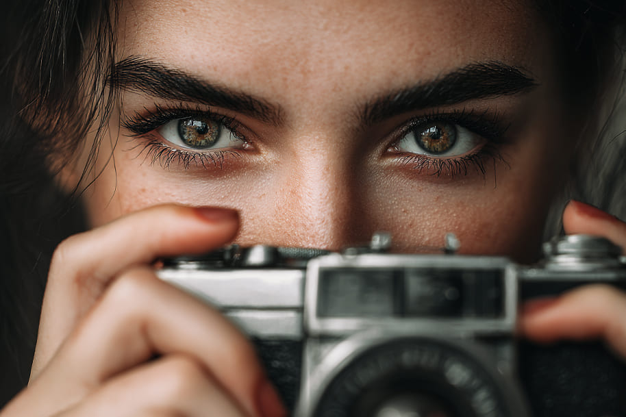 Woman holding a camera and looking directly into the lens, representing society’s fascination with fame, media influence, and the psychology behind celebrity obsession on Eternal Slots Casino’s lifestyle blog.