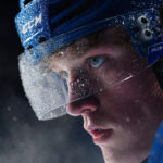 Close-up of a focused ice hockey player in blue gear with frost on his visor, symbolizing determination and intensity. Featured in Eternal Slots Casino’s blog post “Top NHL Players to Watch in 2025: Rising Stars and Season Favorites”, exploring the best NHL talents of 2025.