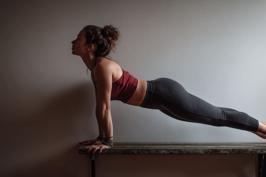 Fit woman in workout clothes practicing wall Pilates pose, demonstrating balance and posture alignment during a home Pilates session.