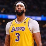 Anthony Davis in an NBA game wearing his Los Angeles Lakers jersey, focused on the court under arena lights, representing his impact and legacy in the league.